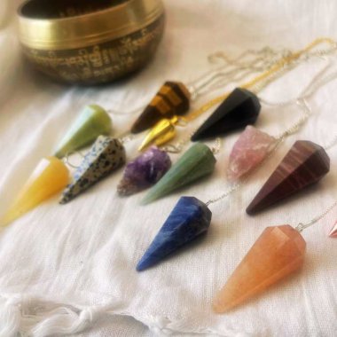 En masse penduler ligger p hvidt stof med en lille klang skl i baggrunden